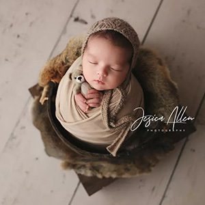 A professional photo of a newborn in a cloth basket wrapped in a tan cloth